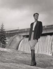 Image of a woman posing in front of a hydroelectric dam.