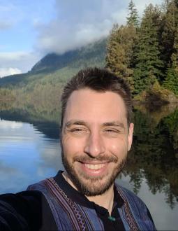 Selfie of Brandon Weigel by a lake. He is smiling at the camera.