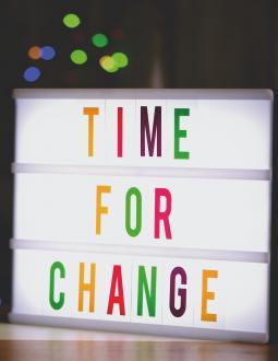 Sign that reads "Time for Change". Coloured lights are in the background.