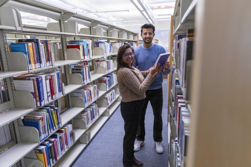 A library worker hands a book to a student in the library stacks of Camosun College.